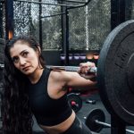 A determined woman lifting weights in a modern gym, embodying fitness and strength.